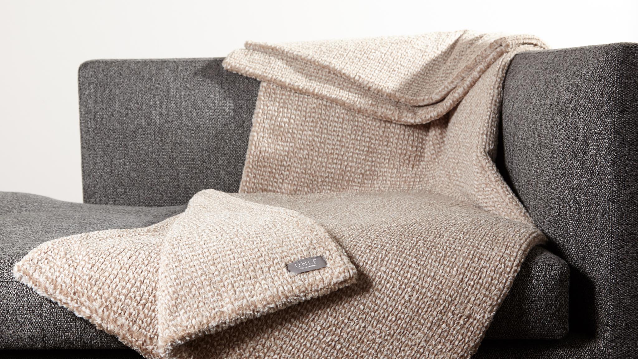 Cortina Sand braun hellbraun herrlich weiche kuschlige exklusive Webfelldecke Webfelldecke elegant in außergewöhnlicher Strickoptik auf petrol Sessel