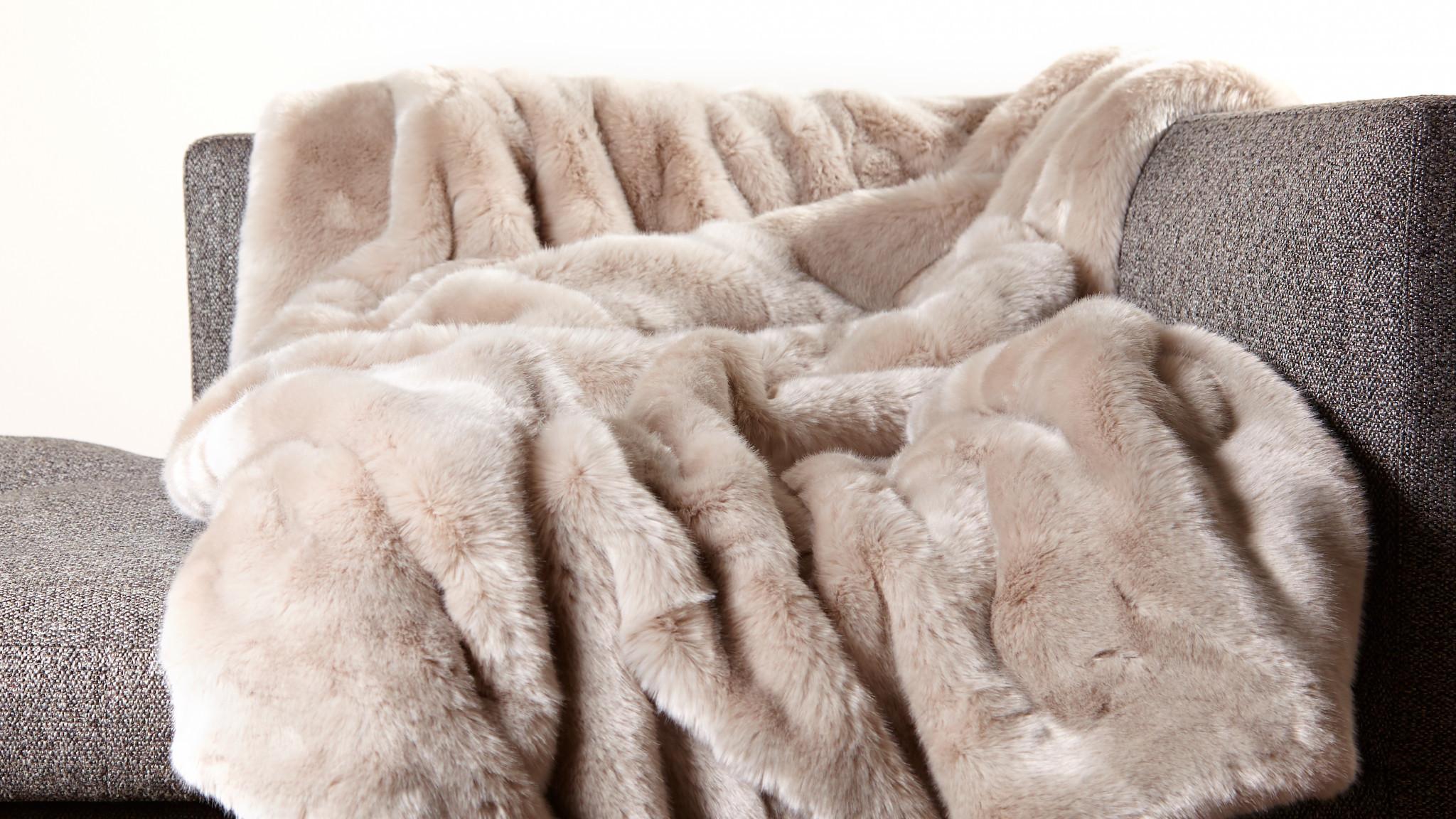 Hochflorige Webpelzdecke hellgrau hellbraun beige sehr weich kuschlig warm auf dem Wohnzimmer Sofa mit Fütterung aus hochwertiger hellgrauer Schurwolle